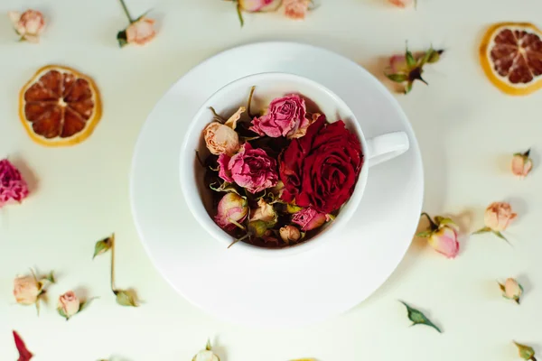 Getrocknete Blumen getrocknete Rosen und runde Zitronenscheiben auf weißem Hintergrund und die weiße Tasse — Stockfoto