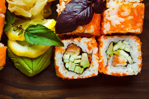 Bela comida chinesa e rolos de sushi em fundo de madeira — Fotografia de Stock