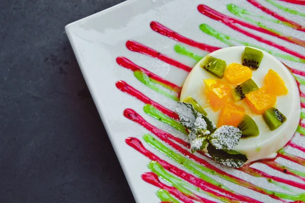 Foto da sobremesa italiana panna cotta com fatias de kiwi, laranja e folha de hortelã — Fotografia de Stock