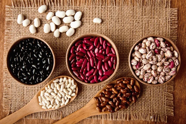 Krásné pestrobarevným fazole v keramické misky na pozadí pytlovina — Stock fotografie