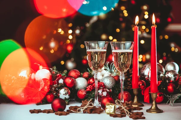 Χριστούγεννα ακόμα ζωή - δύο ποτήρια σαμπάνιας με Χριστούγεννα στολίδια και το χριστουγεννιάτικο δέντρο σε θολή φόντο κόκκινο — Φωτογραφία Αρχείου