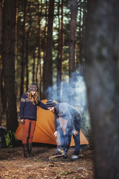 Excursionistas de pie cerca del fuego en la madera —  Fotos de Stock