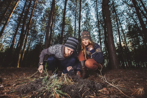 Couple of hikers starting a fire in the wood — Stock Photo, Image