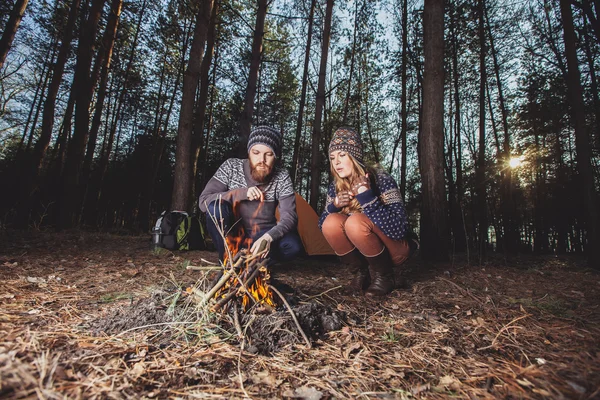 Couple of hikers starting a fire in the wood — Stock Photo, Image