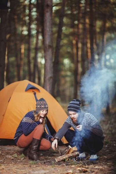 Couple of hikers starting a fire in the wood — Stock Photo, Image