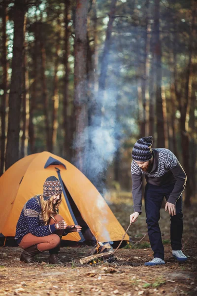 Couple of hikers starting a fire in the wood — Stock Photo, Image