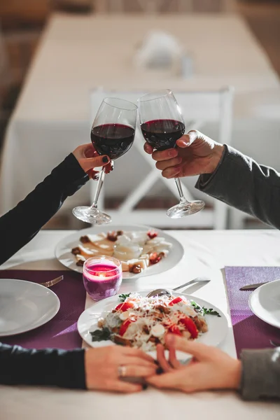 Belo jovem casal com copos de vinho tinto em restaurante de luxo — Fotografia de Stock