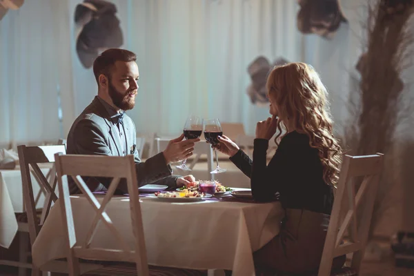 Belo jovem casal com copos de vinho tinto em restaurante de luxo — Fotografia de Stock