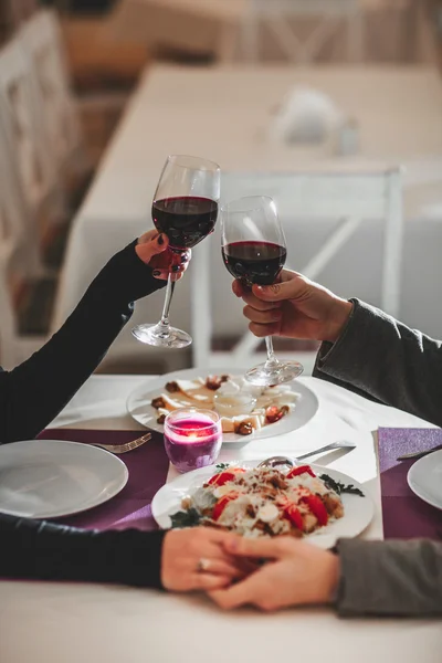 Hermosa pareja joven con copas de vino tinto en un restaurante de lujo —  Fotos de Stock