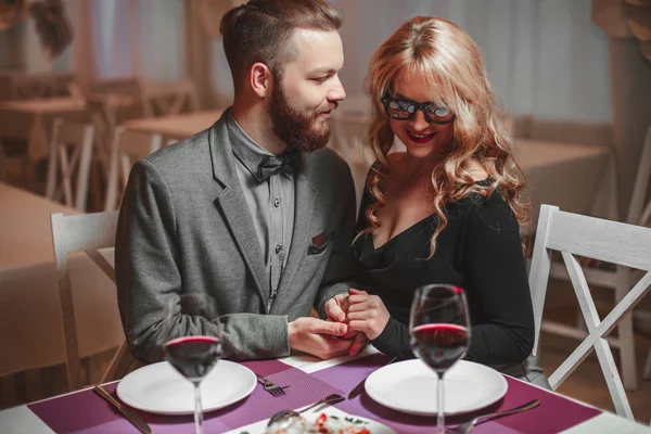 Hermosa pareja joven con copas de vino tinto en un restaurante de lujo —  Fotos de Stock