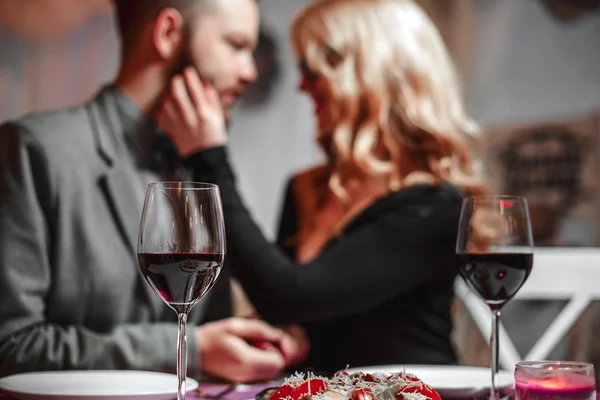 Mooie jonge paar met glazen rode wijn in luxe restaurant — Stockfoto