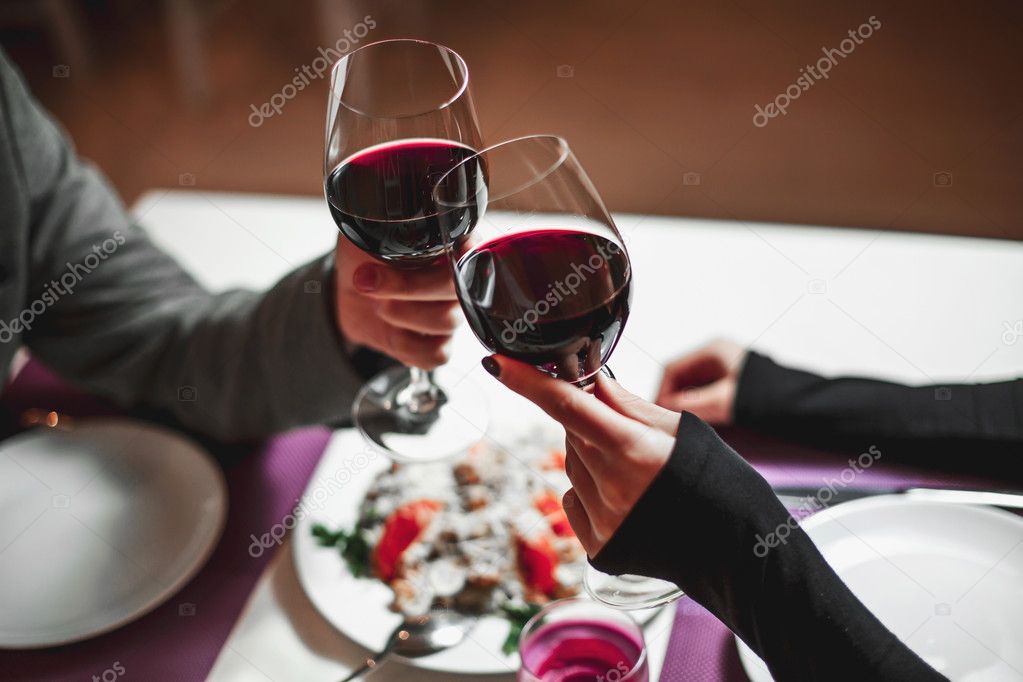 Beautiful young couple with glasses of red wine in luxury restaurant