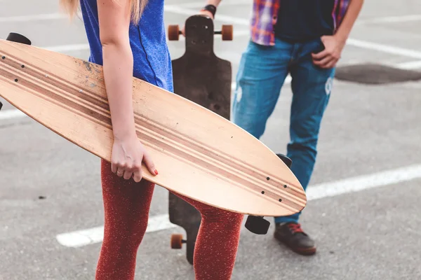 Молодая пара держит скейтборд снаружи — стоковое фото