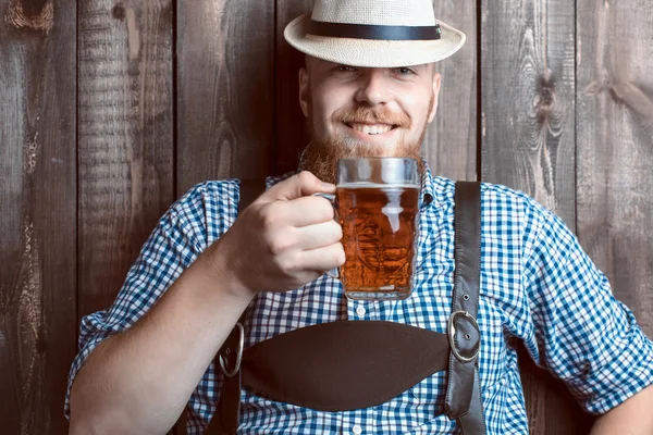 Felice uomo sorridente con pantaloni di pelle degustazione birra fresca prodotta . — Foto Stock