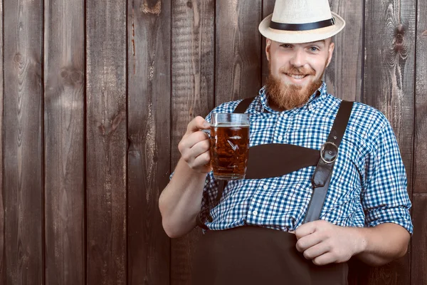 Felice uomo sorridente con pantaloni di pelle degustazione birra fresca prodotta . — Foto Stock