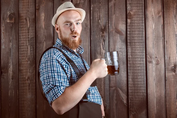 Feliz hombre sonriente con pantalones de cuero (lederhose) degustación de cerveza recién hecha . — Foto de Stock