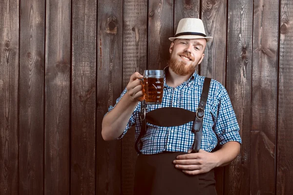 快乐的男人微笑着与皮革长裤 (lederhose) 持有慕尼黑啤酒节啤酒玻璃 — 图库照片