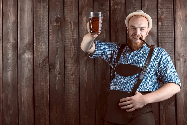 Szczęśliwy uśmiechający się człowiek z Spodnie skórzane (lederhose) posiada szkło piwa oktoberfest — Zdjęcie stockowe