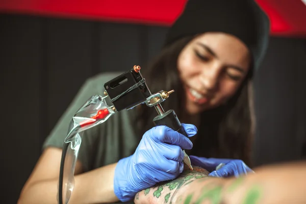 Vacker brunett flicka gör tatuering. Tatuerare gör en tatuering. Närbild — Stockfoto