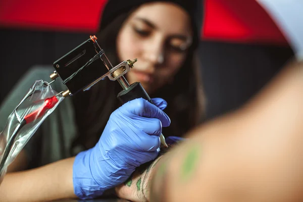 Mooie brunette meisje maakt tatoeage. Tatoeëerder maakt een tatoeage. Closeup — Stockfoto