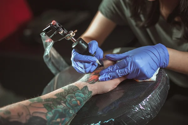Красивая брюнетка делает татуировку. Татуировщик делает татуировку. Крупный план — стоковое фото
