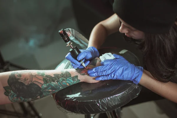 Красивая брюнетка делает татуировку. Татуировщик делает татуировку. Крупный план — стоковое фото