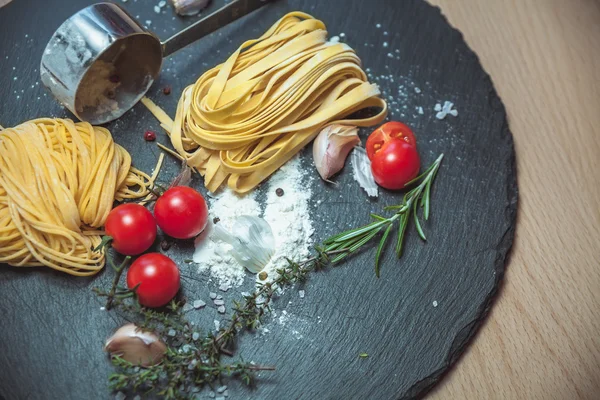 Beaux spaghettis frais sur le tableau noir aux épices et tomates — Photo