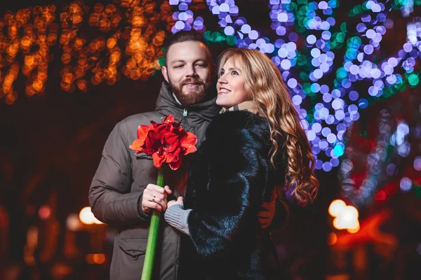 Loving young couple walking outdoors in winter. Girl holding a flower — Stock Photo, Image