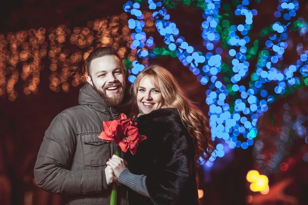 Amando jovem casal andando ao ar livre no inverno. Menina segurando uma flor — Fotografia de Stock