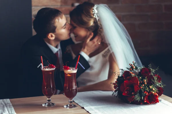 Beautiful red cocktail with cherries and wedding rings, behind the bride with a wedding bouquet of red roses — Stock Photo, Image