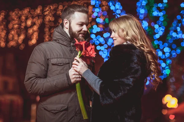 Liebende junge Pärchen, die im Winter draußen spazieren gehen. Mädchen mit einer Blume — Stockfoto