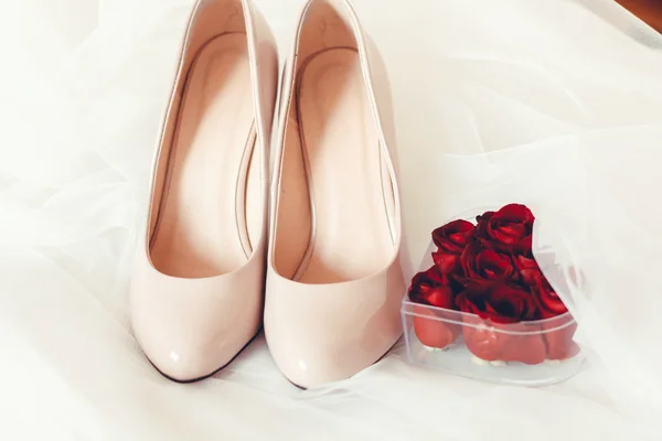 Wedding shoes with rings and red rose petals — Stock Photo, Image