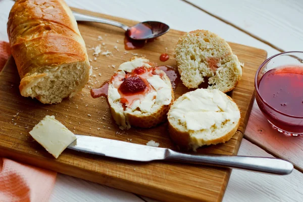 Toasts with jam on plate and cup of tea on bright background — Stock Photo, Image