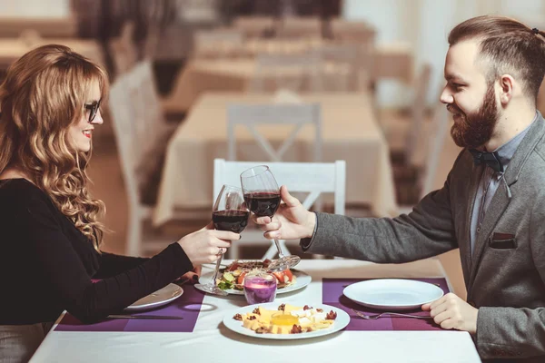 Όμορφο νεαρό ζευγάρι με ποτήρια κόκκινο κρασί σε πολυτελές εστιατόριο — Φωτογραφία Αρχείου