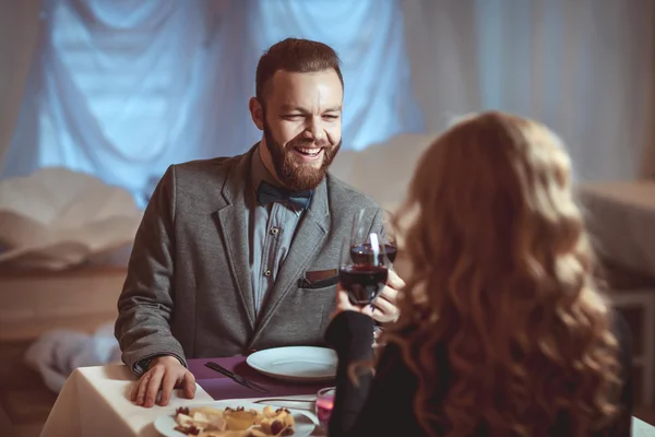 Beautiful young couple with glasses of red wine in luxury restaurant — Stock Photo, Image