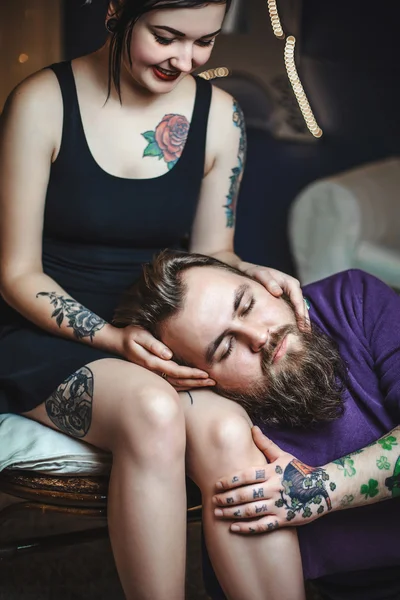 Jeune couple amoureux de tatouages, le gars est allongé sur les genoux de la fille — Photo