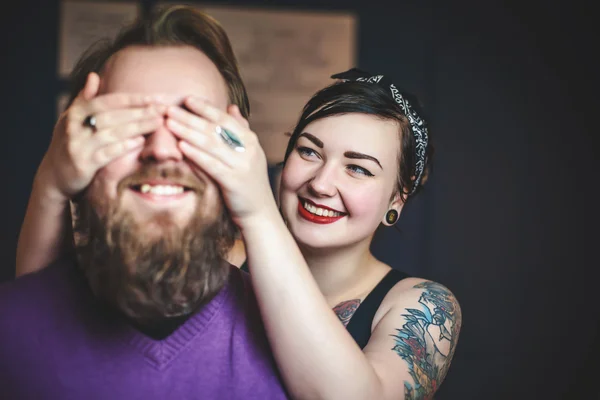 Young couple in love with tattoos having fun, the girl closes hands eyes guy — Stock Photo, Image