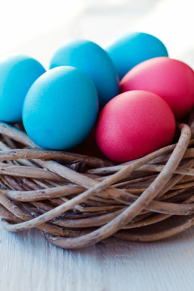 흰색 나무 바탕에 둥지에 파란색과 분홍색 부활절 달걀 — 스톡 사진