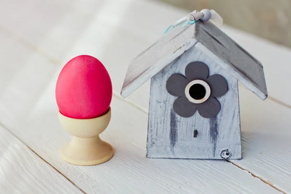 Colore Uova di Pasqua in nido su sfondo bianco in legno con birdhouse — Foto Stock