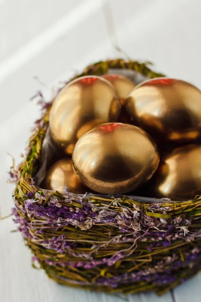 Gouden Pasen eieren in nest op witte houten achtergrond — Stockfoto