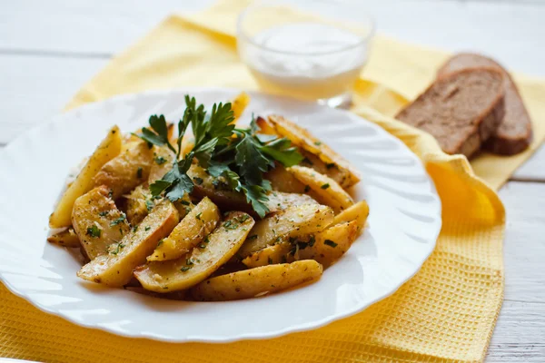 Beautiful roasted potatoes with herbs and spices on a white plate — Stock Photo, Image