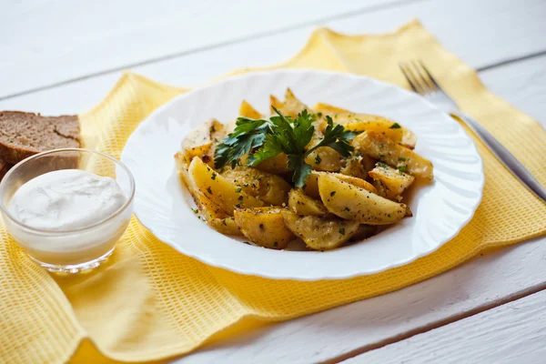 Beautiful roasted potatoes with herbs and spices on a white plate — Stock Photo, Image