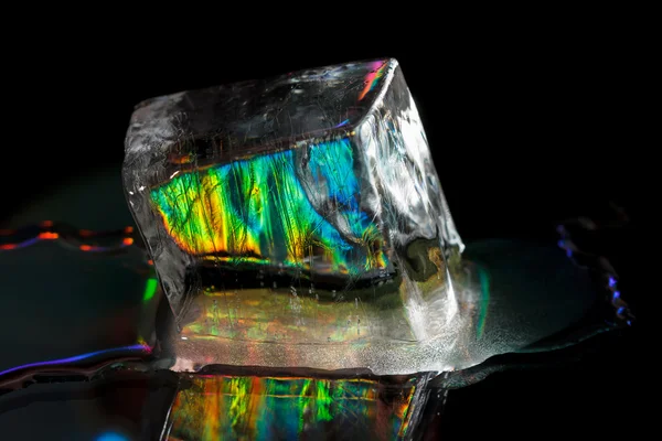 Un grande cubo di ghiaccio colorato isolato sul nero — Foto Stock