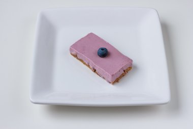 Beyaz bir arka plan beyaz bir plaka üzerinde yaban mersinli cheesecake