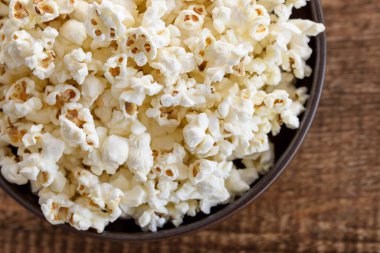 Bir kase patlamış mısır, üst manzara, sıcak renkler, açık kahverengi ahşap arka plan, düz yatak, gün ışığı makro yakın çekim