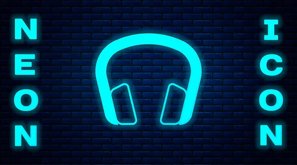 Glödande neon hörlurar ikonen isolerad på tegel vägg bakgrund. Hörlurar. Koncept för att lyssna på musik, service, kommunikation och operatör. Vektor — Stock vektor
