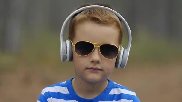 Usměvavý chlapeček v sluchátka venkovní na léto — Stock video