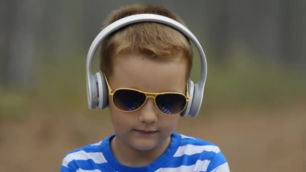 Liten pojke lyssna på musik utomhus, sommartid — Stockvideo