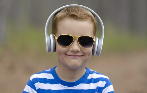 Lächelnder kleiner Junge mit Kopfhörern im Sommer draußen — Stockfoto