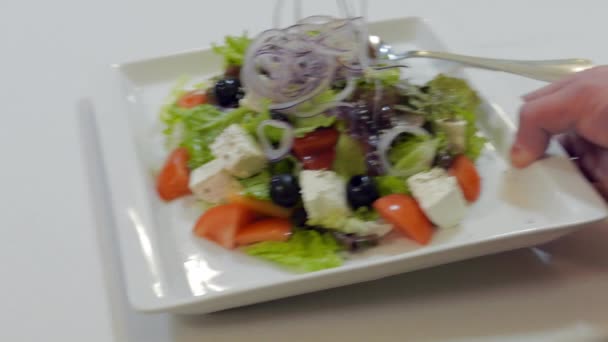 Servitören lägger en tallrik med grekisk sallad på bord, på restaurang — Stockvideo